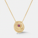 A gold spiral pendant necklace featuring a small round pink gemstone at the center, suspended from a delicate gold chain against a light gray background.