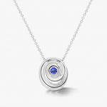 A silver spiral pendant necklace featuring a central round blue gemstone, displayed on a clean light gray background.