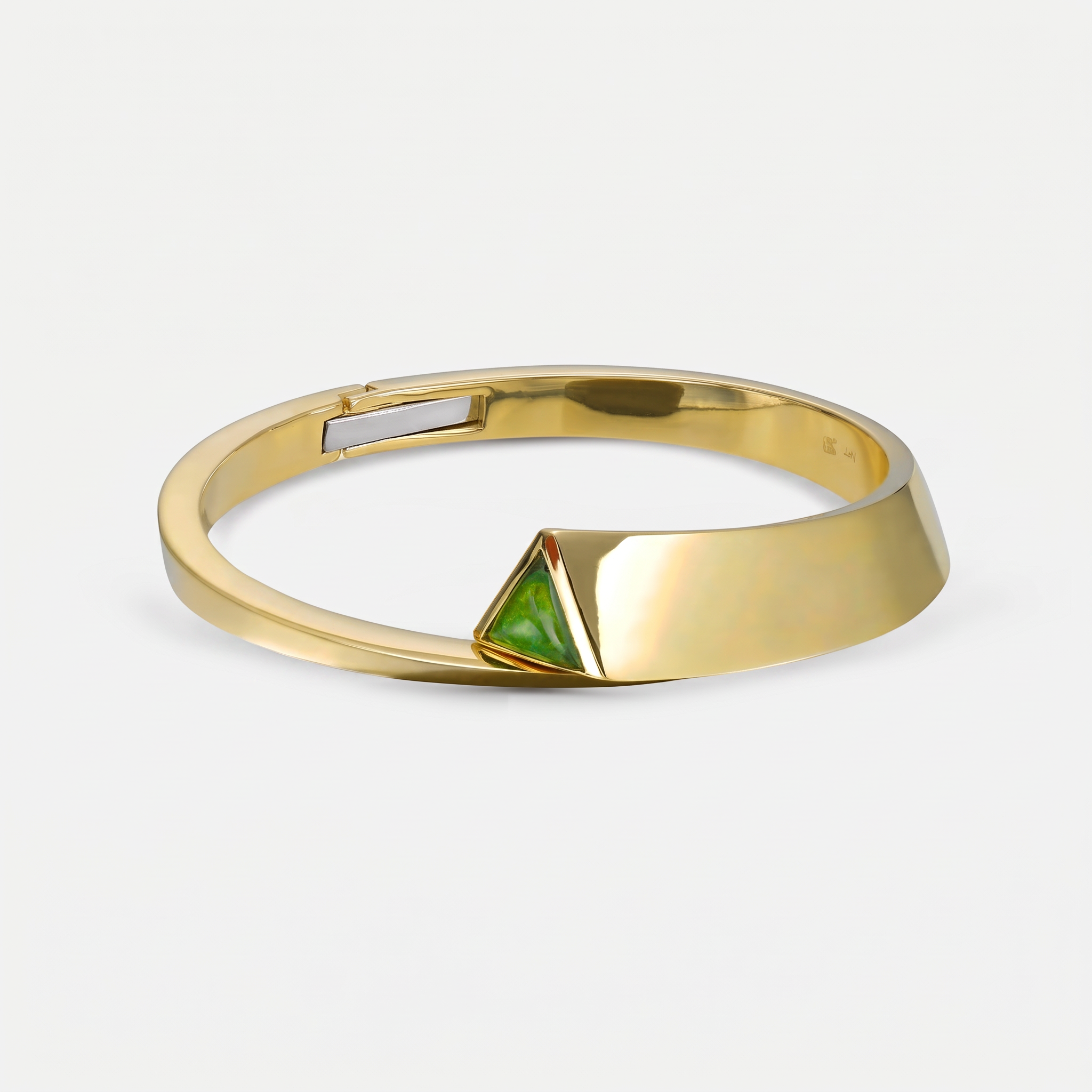 A gold cuff bracelet with a geometric triangular green inlay on the front, shown on a light gray background.
