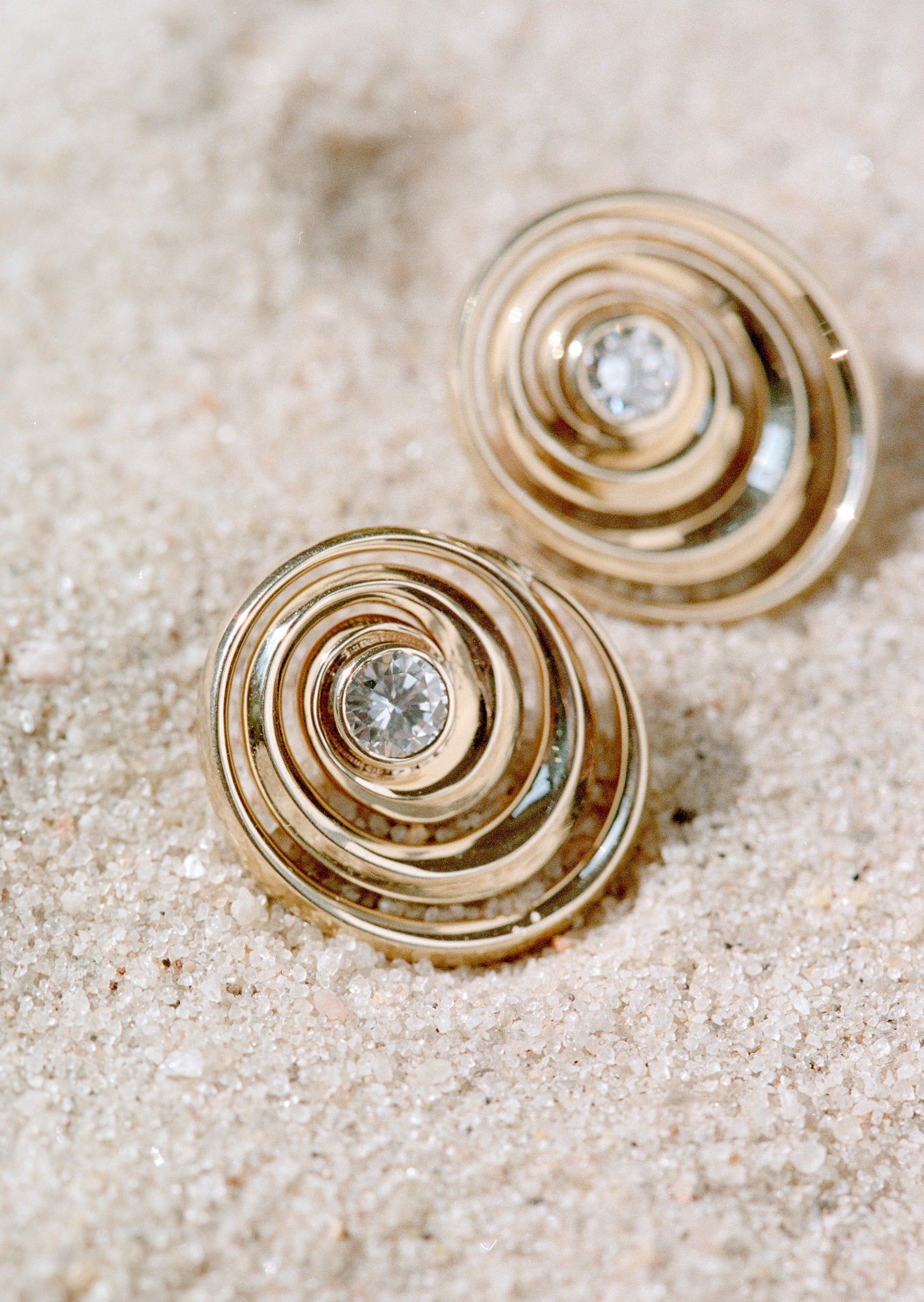 Spiral gold studs with a diamond on the center designed by Isabel Delgado