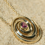 Catalina pendant designed by Isabel Delgado in a shape of a swirl crafted in gold and set with a pink tourmaline