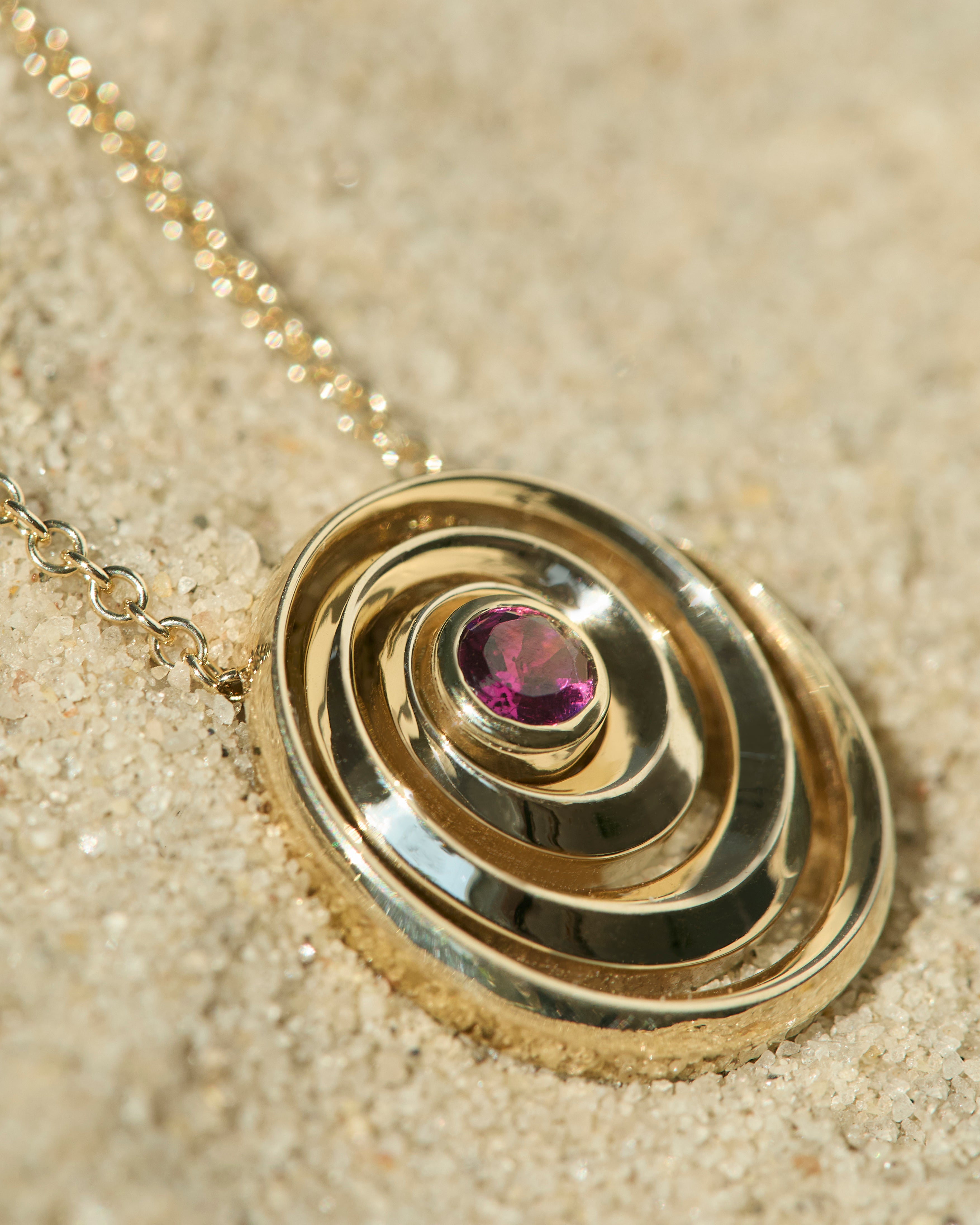 Catalina pendant designed by Isabel Delgado in a shape of a swirl crafted in gold and set with a pink tourmaline