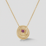 A gold spiral pendant necklace featuring a small round pink gemstone at the center, suspended from a delicate gold chain against a light gray background.