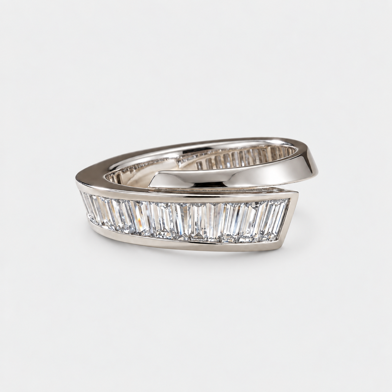 A silver wrap-style ring featuring a row of clear baguette-cut diaonds on the front, photographed on a clean light gray background.