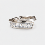 A silver wrap-style ring featuring a row of clear baguette-cut diaonds on the front, photographed on a clean light gray background.