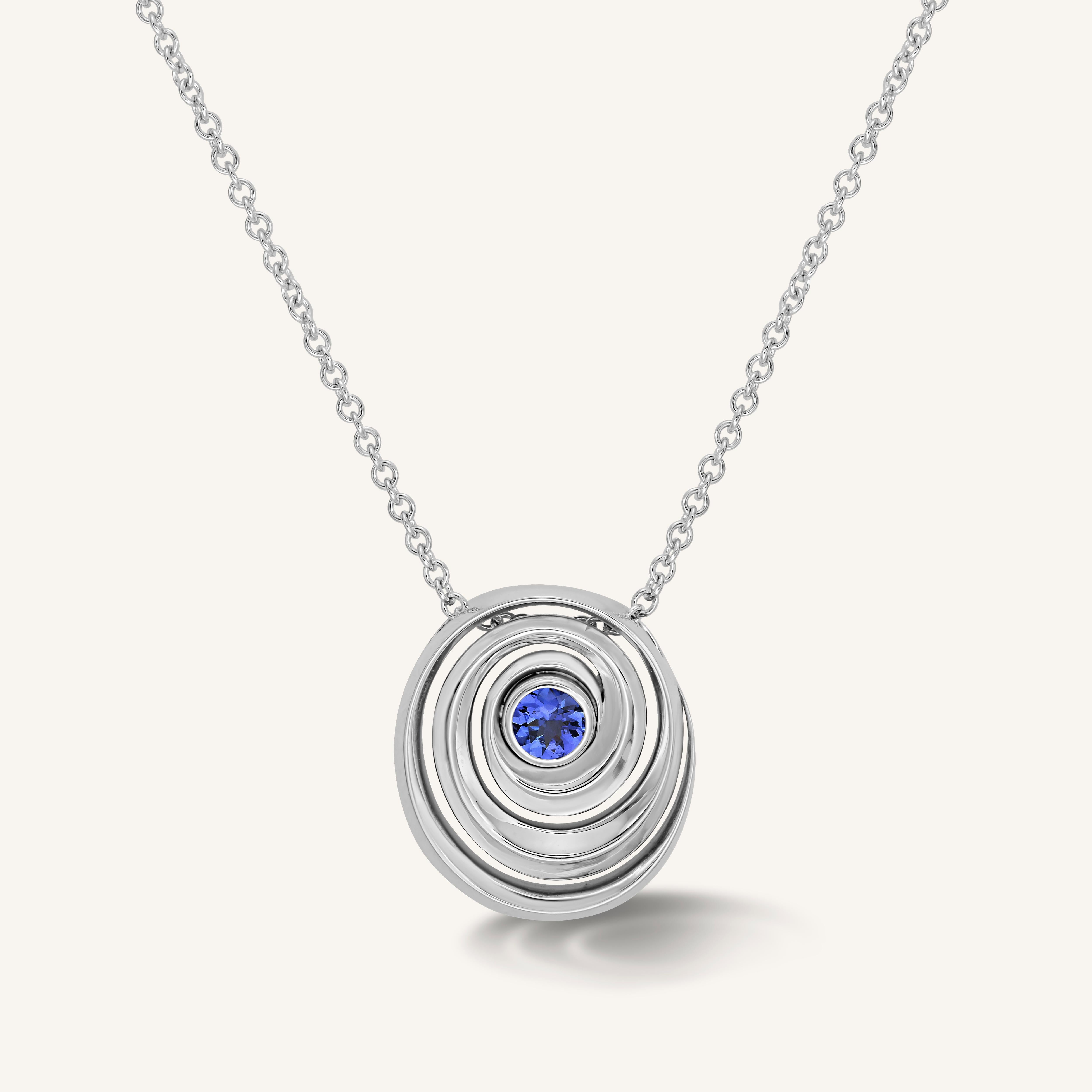 gold spiral pendant set with a tanzanite in the center designed by Isabel Delgado