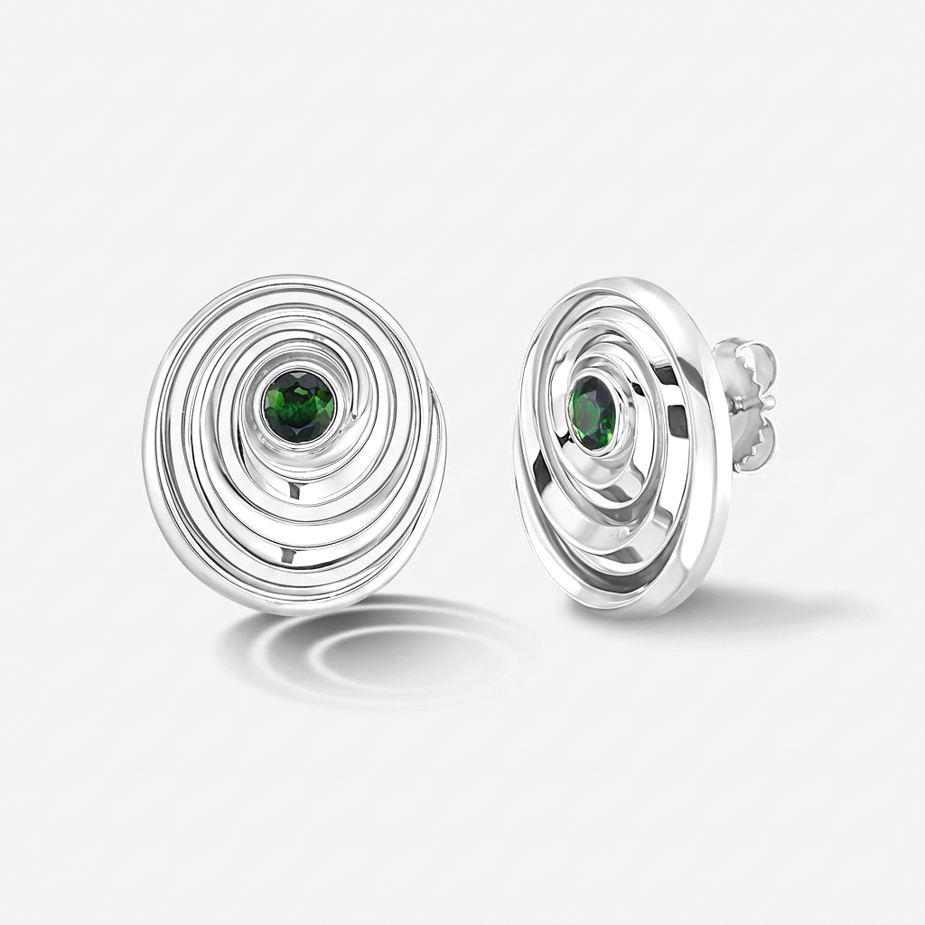 A pair of white gold spiral stud earrings with a small round green gemstone in the center, shown on a light gray background.