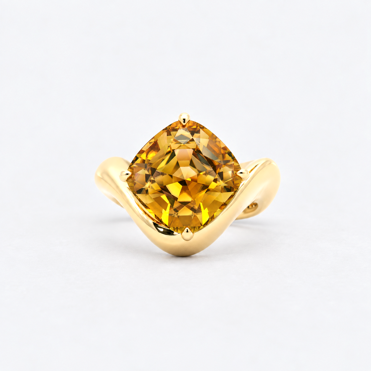 A yellow gold ring featuring a cushion-cut yellow gemstone in a prong setting, displayed on a clean light gray background.