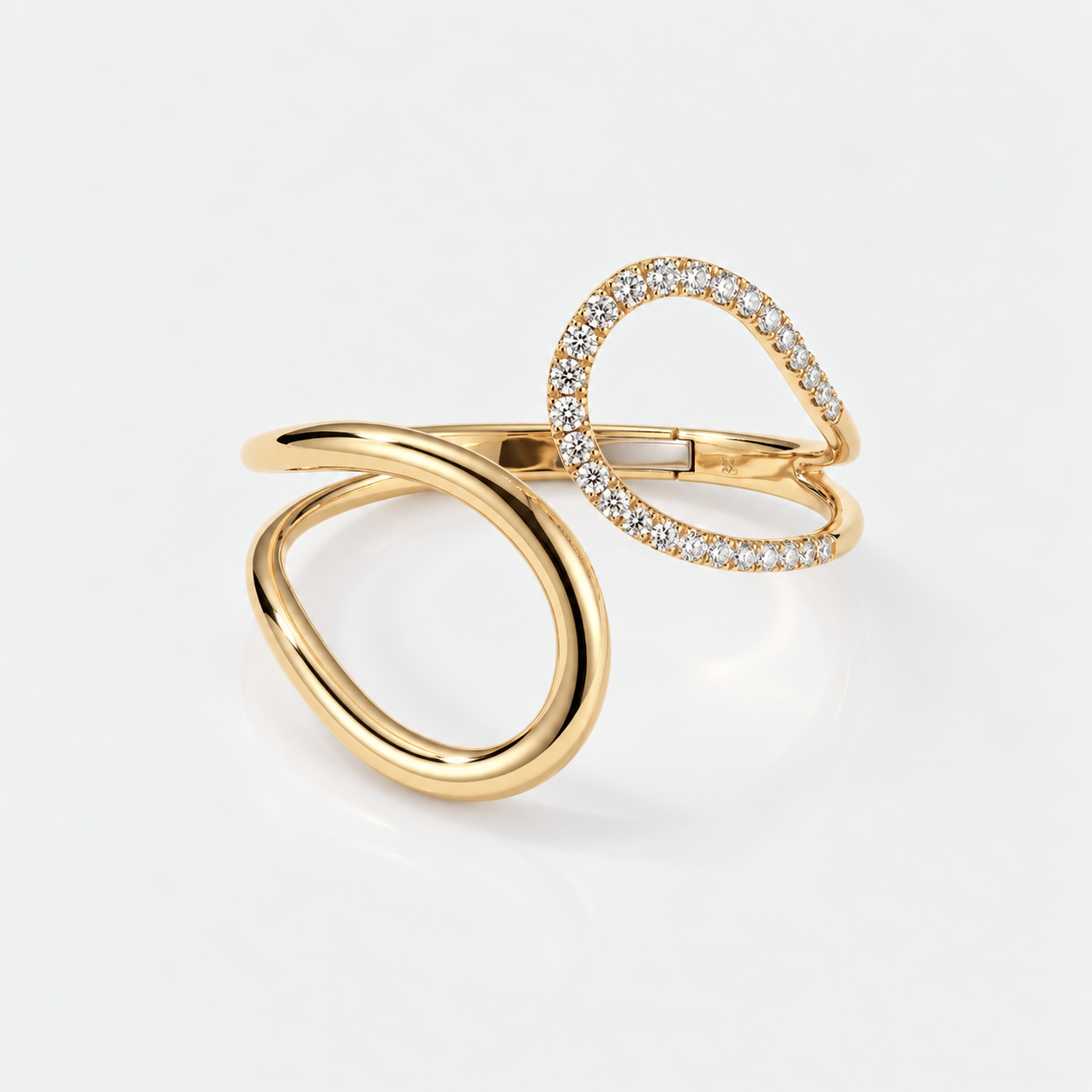 A gold open wrap ring featuring one smooth loop and one pavé-set diamond loop, photographed on a clean white background.