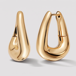 A pair of polished gold huggie hoop earrings with a teardrop-shaped organic design, shown on a light gray background.