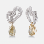 A pair of heart-shaped drop earrings featuring pavé-set white gold metal, clear stones, and pear-cut yellow diamonds hanging from gold-toned prongs, shown on a light gray background.
