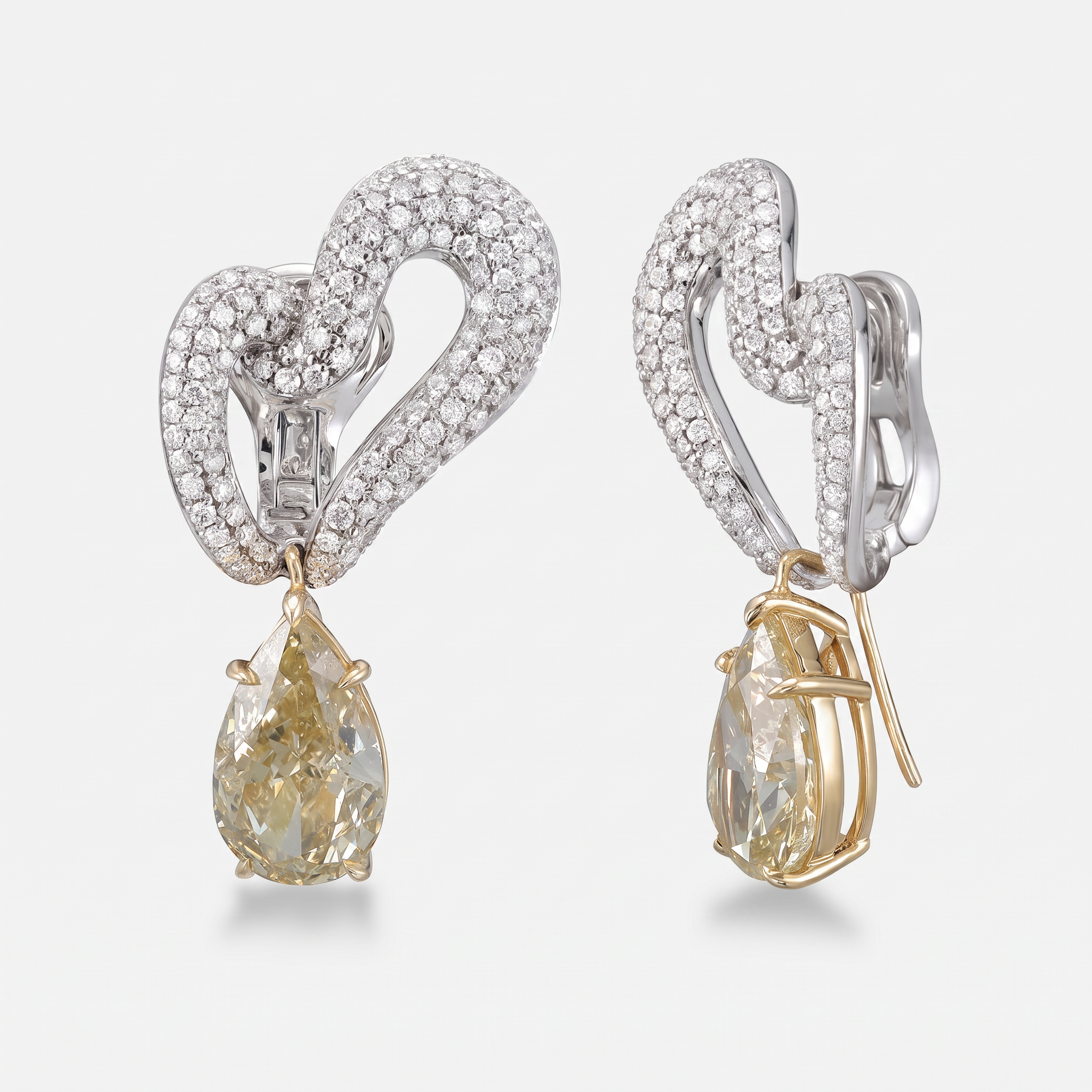 A pair of heart-shaped drop earrings featuring pavé-set white gold metal, clear stones, and pear-cut yellow diamonds hanging from gold-toned prongs, shown on a light gray background.