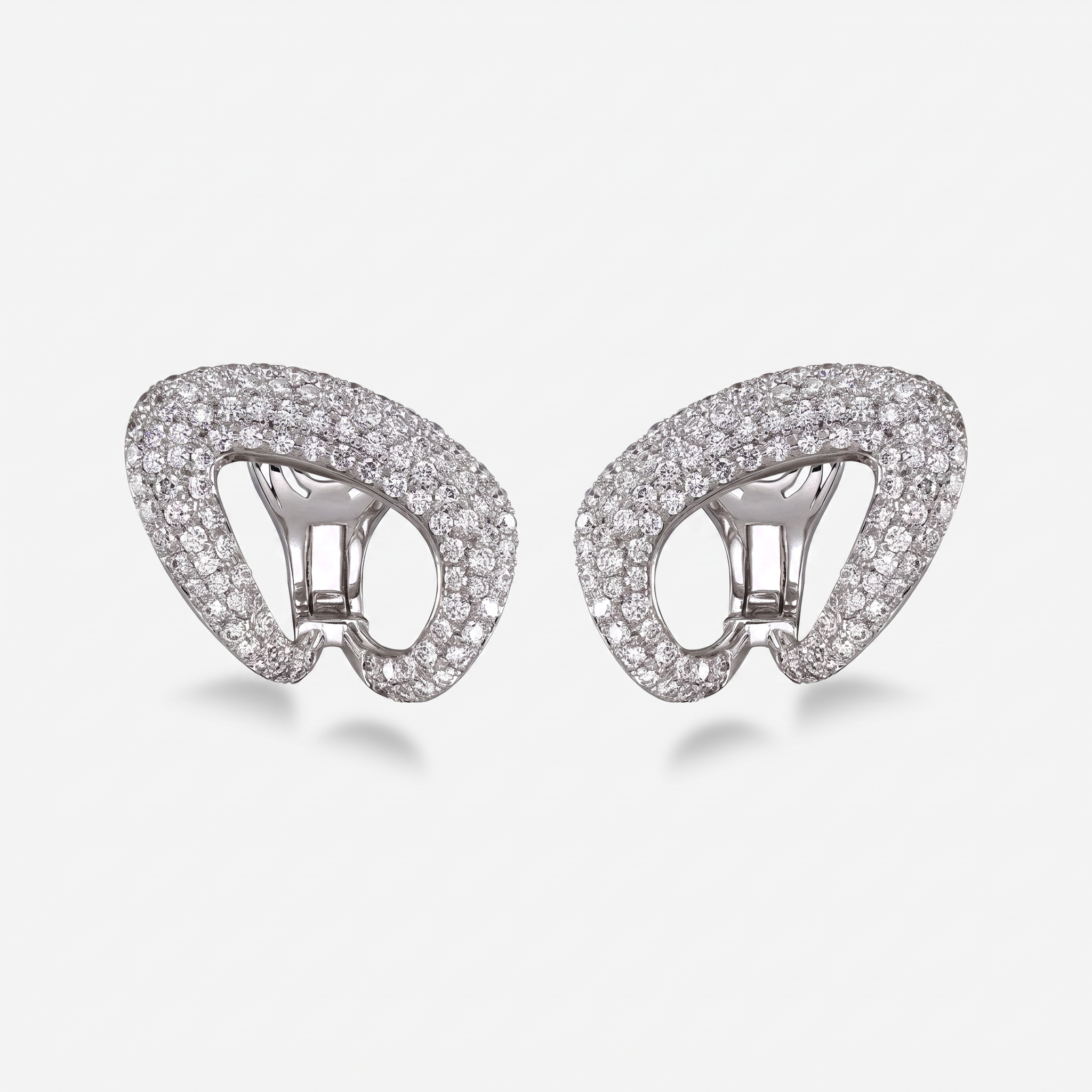 A pair of white gold clip-on earrings paved with white diamonds, shown against a light gray background.