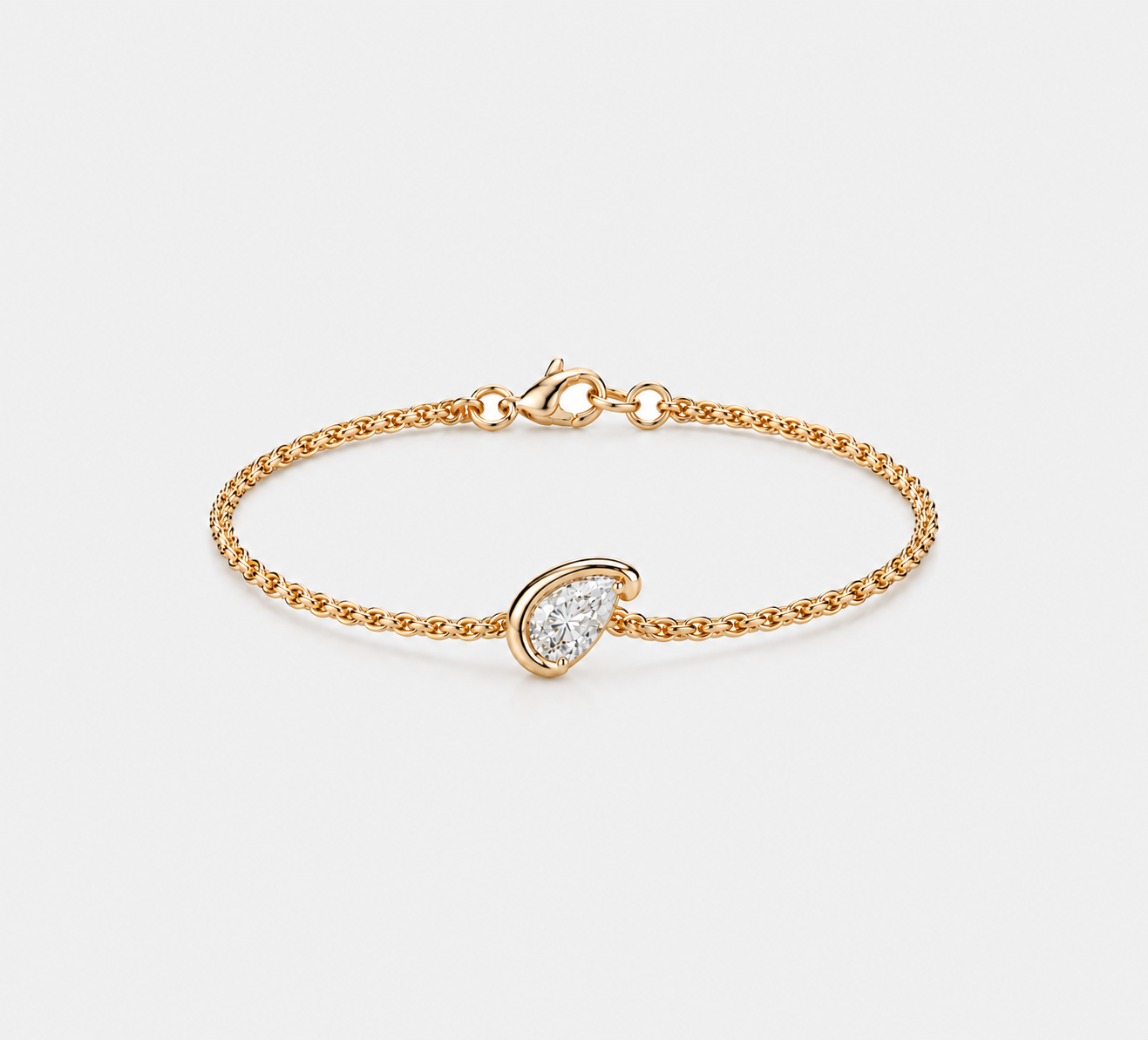 A delicate gold chain bracelet with a small pear-shaped clear gemstone pavé-set in a gold bezel, shown on a light gray background.