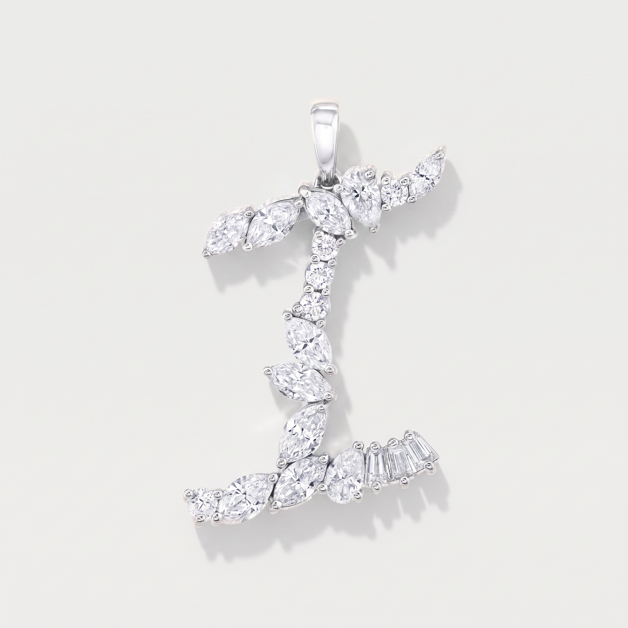 A white gold pendant shaped like the letter 'I', adorned mixed cut diamonds, shown on a light gray background.