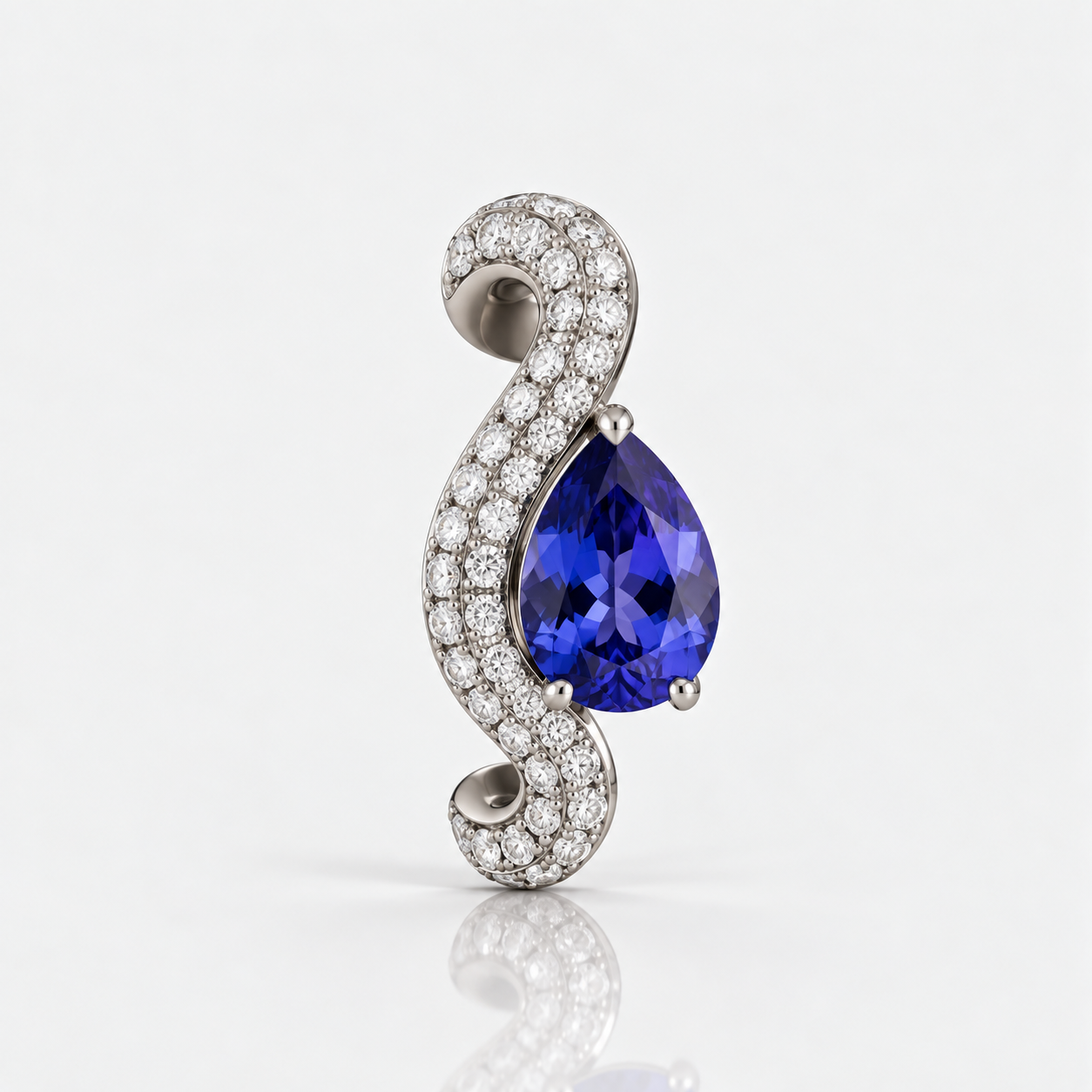A teardrop-shaped blue gemstone pendant set in a silver-toned metal with a curved pavé border of small clear stones, photographed on a clean white background with a soft reflection below.