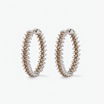 A pair of large hoop earrings with white and champagne diamonds set in polished white-toned metal. The earrings are displayed on a clean, light gray background.