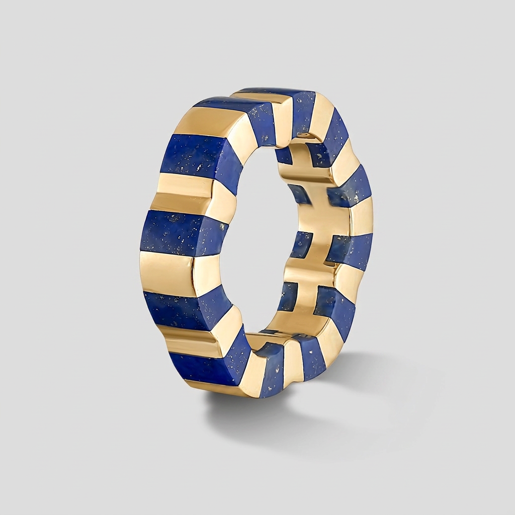 A modern geometric ring featuring alternating textured gold and deep blue lapis lazuli strips, shown on a neutral light gray background.