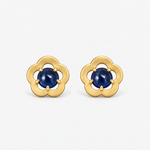 A pair of gold flower-shaped stud earrings with round sapphirescabochon gemstones in the center, set against a clean white background.