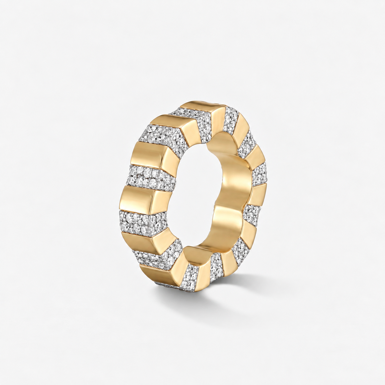 A modern geometric ring made of yellow gold with pavé-set clear stones, shown on a clean light gray background.
