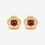 A pair of gold flower-shaped stud earrings with round red gemstones in the center, set against a clean white background.