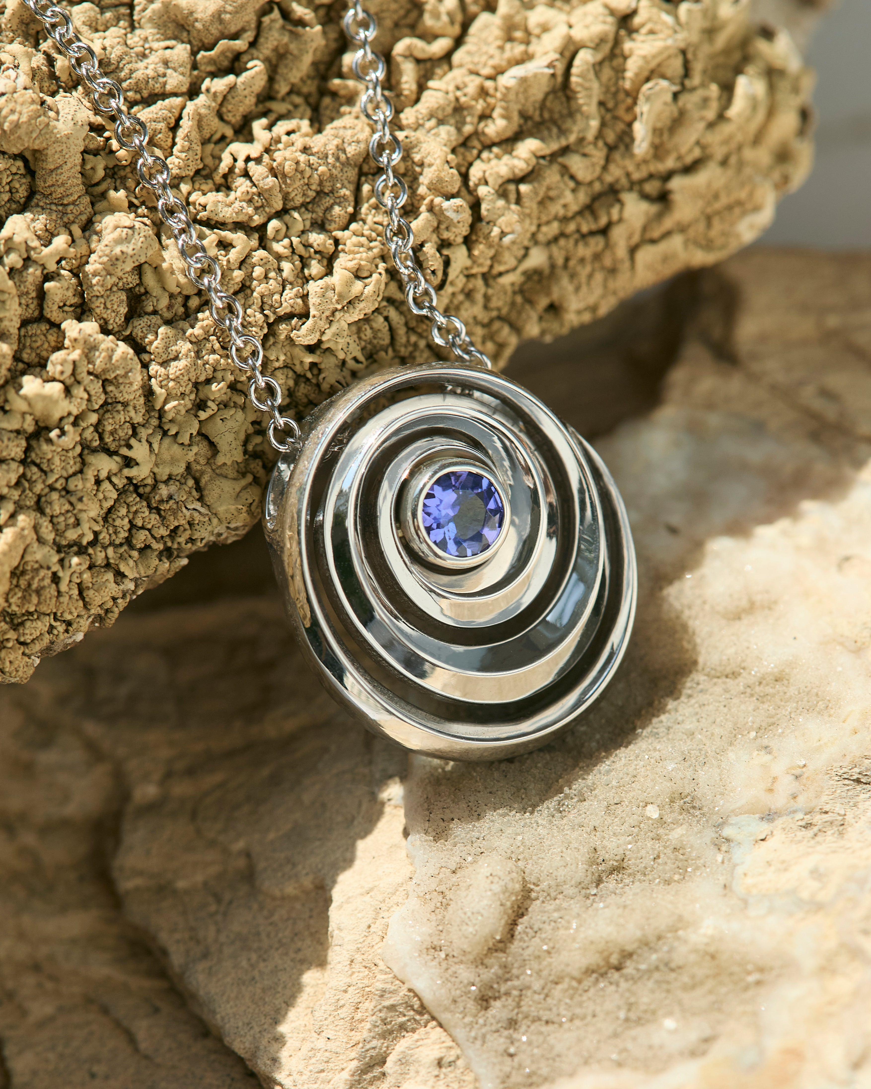gold spiral pendant set with a tanzanite in the center designed by Isabel Delgado