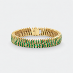 A yellow gold tennis bracelet featuring rows of round-cut green emerald-cut gemstones, displayed on a clean light gray background.