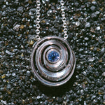 gold spiral pendant set with a tanzanite in the center designed by Isabel Delgado