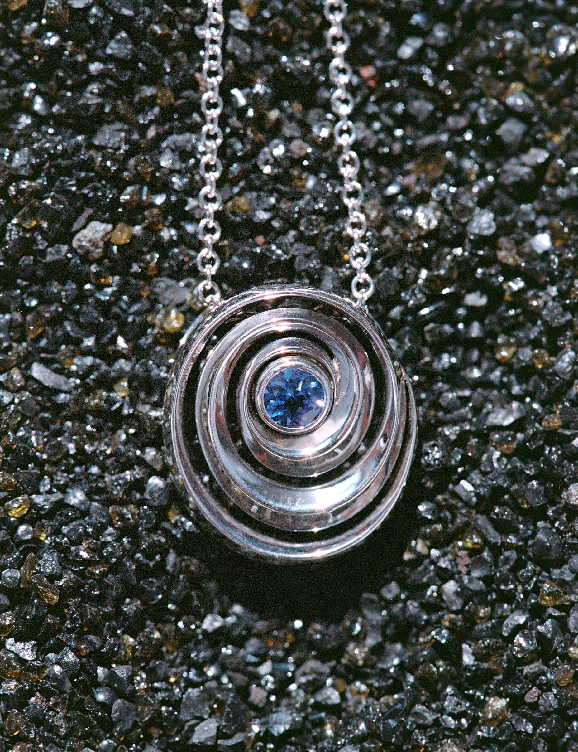 gold spiral pendant set with a tanzanite in the center designed by Isabel Delgado