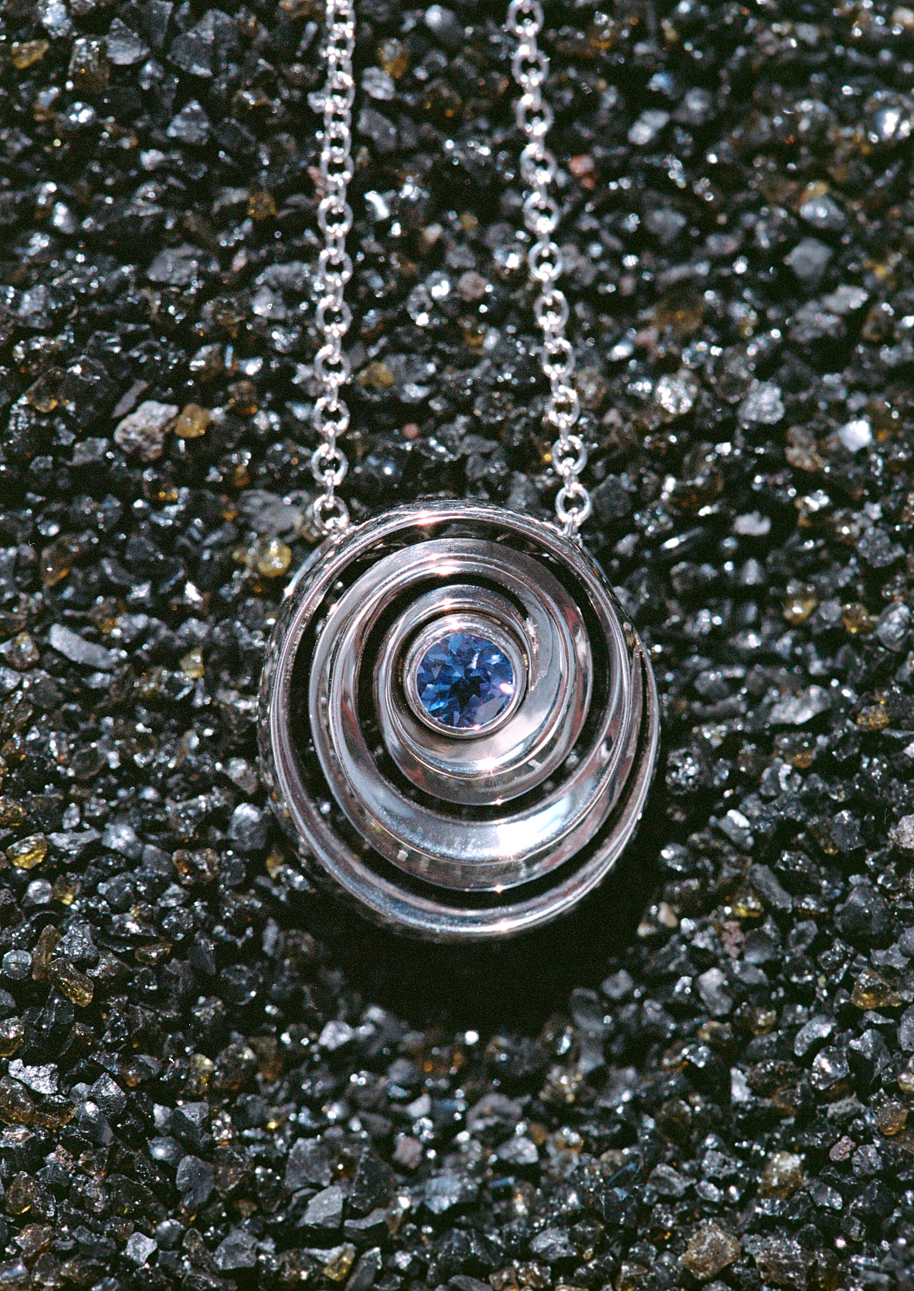gold spiral pendant set with a tanzanite in the center designed by Isabel Delgado