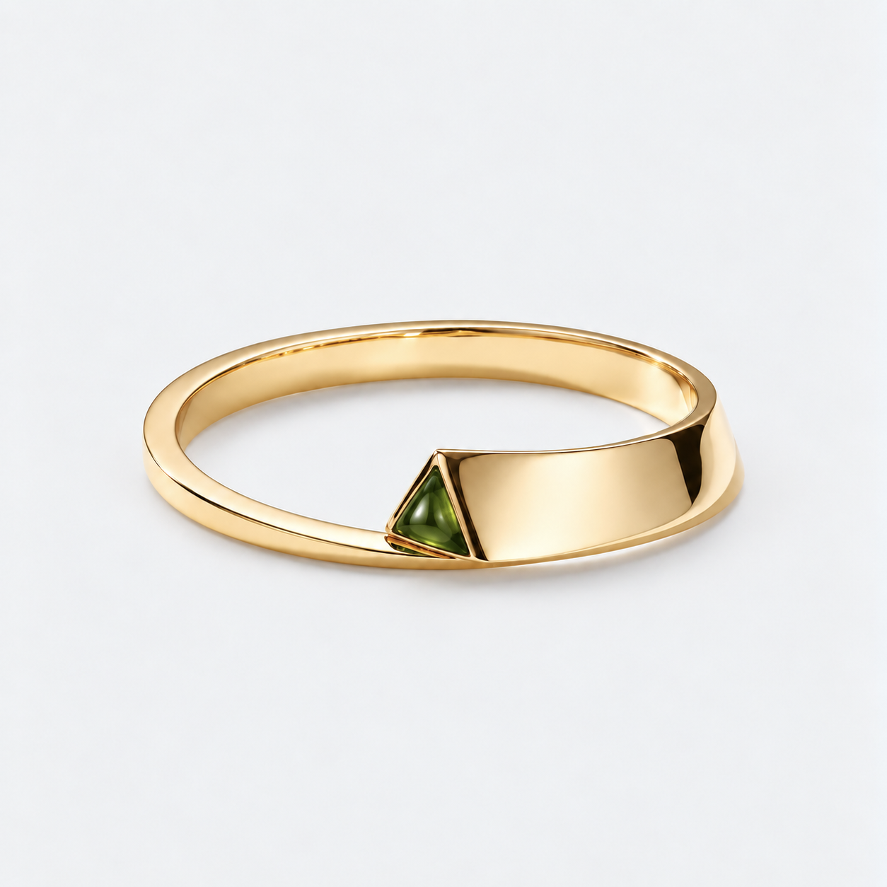 A polished gold cuff with a triangular green gemstone accent, shown on a clean light gray background.