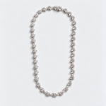 A delicate silver-toned necklace featuring a continuous line of small, flower-like clusters of clear gemstones, laid flat on a clean white background.