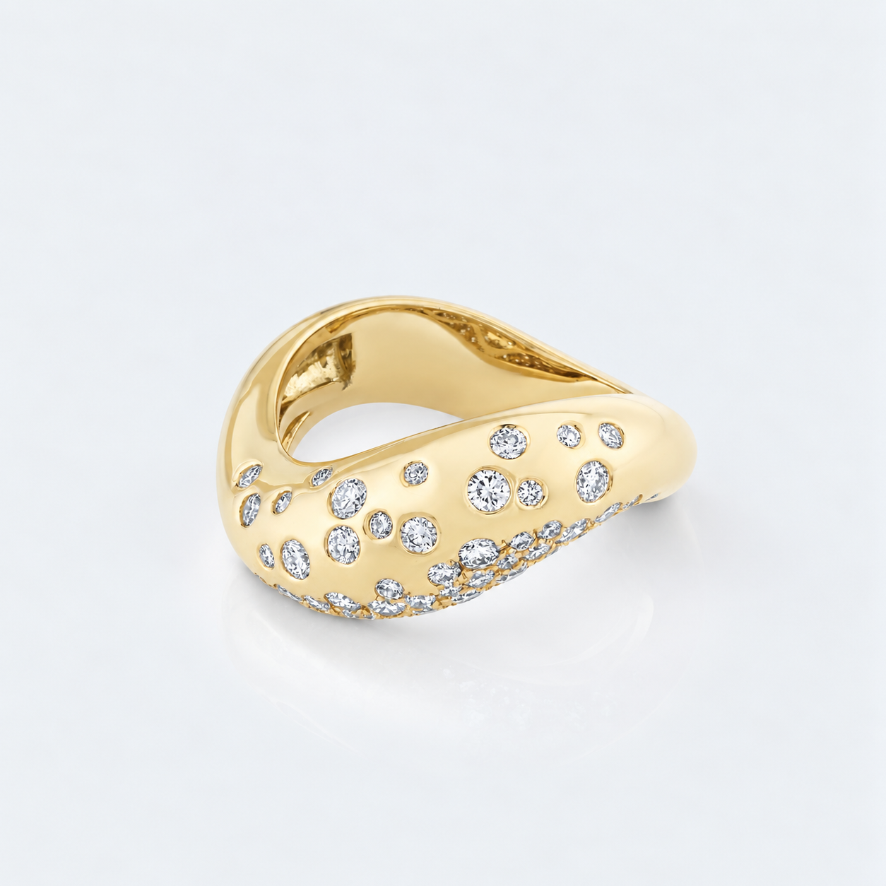 A curved yellow gold ring adorned with multiple small round-cut clear diamonds, photographed on a clean white background with a soft reflection.